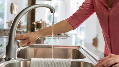 Una mujer abriendo un grifo de agua