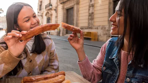 Madre e hija comen porras (churros) en una calle de Madrid