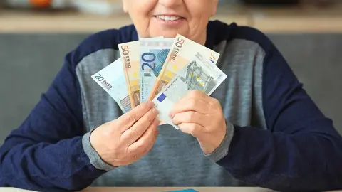 Persona sostiene los billetes cobrados de su pensi&oacute;n