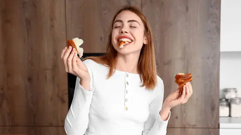 Joven comiendo un sabroso croissant en la cocina