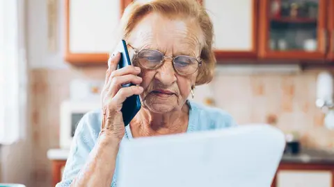 Mujer pensionista preocupada revisa documentaci&oacute;n