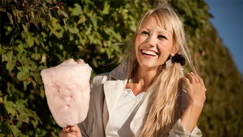 Mujer comiendo algod&oacute;n de az&uacute;car durante una celebraci&oacute;n