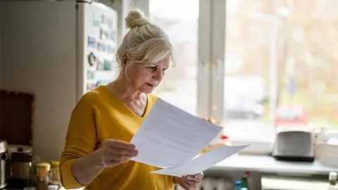 Mujer revisa documentaci&oacute;n en la cocina