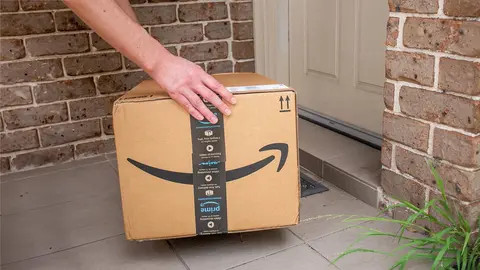 Repartidor deja una caja de Amazon en un domicilio
