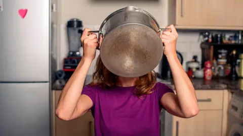 Mujer coge una olla en la cocina