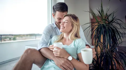 Pareja bebe un par de tazas de caf&eacute; junto a la terraza de su casa