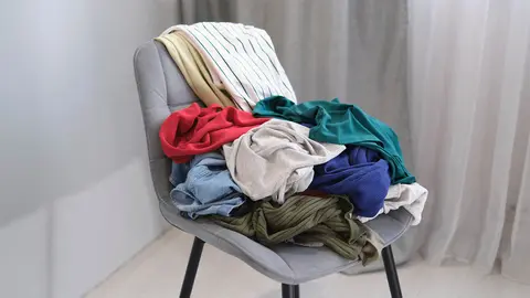 Silla con ropa desordenada en el dormitorio