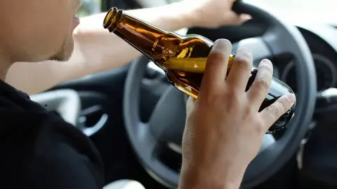 Un hombre conduce con una cerveza en la mano
