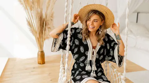 Mujer con vestido boho posando en un dormitorio elegante