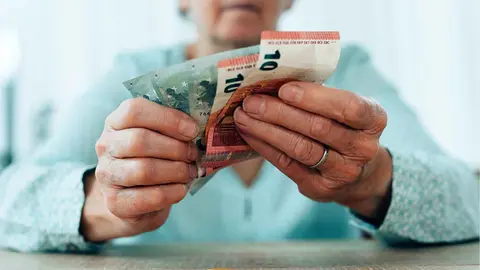 Una pensionista cuenta el dinero de su pensi&oacute;n en el mes de mayo