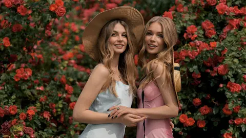 J&oacute;venes elegantes posan en un jard&iacute;n de rosas