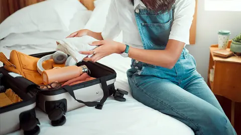 Turista deshace la maleta en la habitaci&oacute;n de hotel