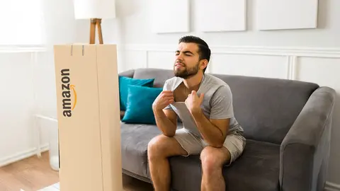 Hombre con calor en el sof&aacute; junto a una caja de Amazon