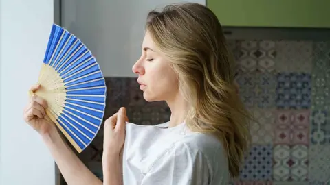 Una mujer con calor abanic&aacute;ndose