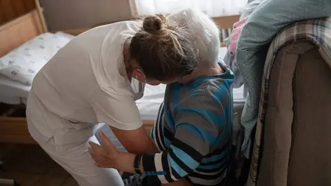 Una enfermera atiende a una anciana en una residencia de mayores
