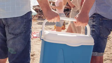 Hombres cargan juntos la nevera en la playa