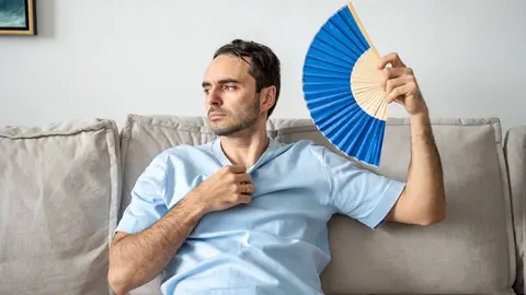 Hombre se abanica en el sof&aacute;