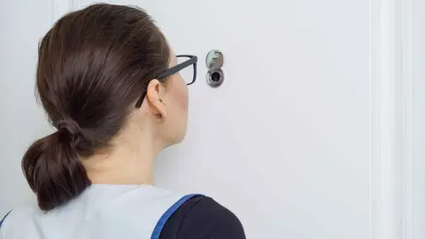 Una mujer mirando por la mirilla de una puerta