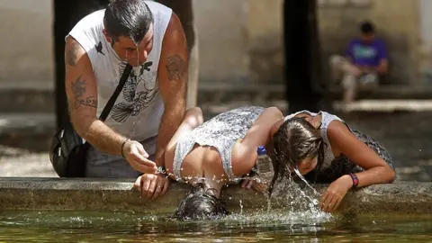 Personas se refrescan en una fuente para combatir el calor