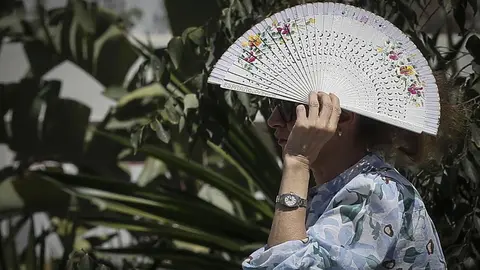 Una mujer se protege del sol con un abanico