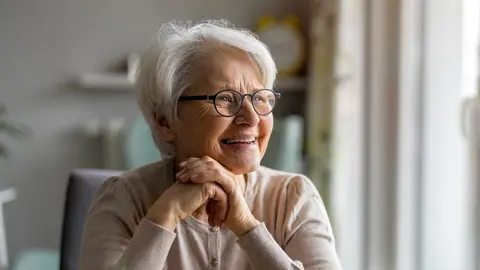 Mujer mayor sonr&iacute;e en su casa