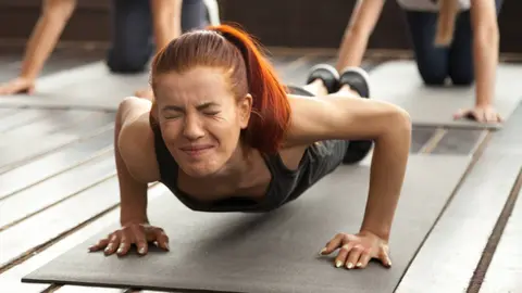 Mujer se esfuerza durante una clase fitness en el gimnasio