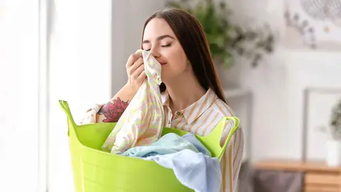 Una mujer huele la ropa limpia gracias al ambientador de Mercadona
