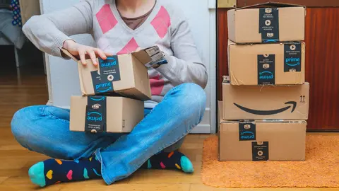Mujer abre paquetes de Amazon junto a la puerta de entrada de la casa