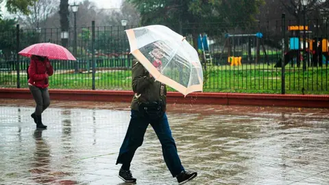 Personas se protegen de la lluvia en Sevilla