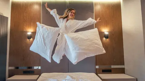 Mujer salta sobre una cama con funda n&oacute;rdica