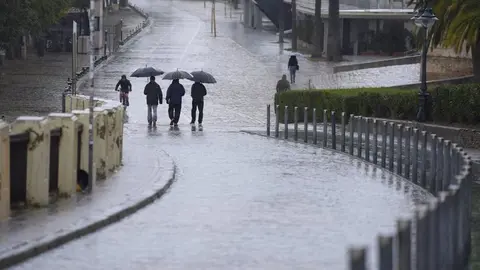 Varias personas se protegen de la lluvia con un paraguas en Sevilla