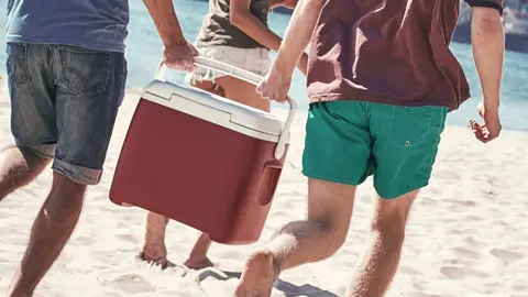 Ba&ntilde;istas llevan la nevera en la playa