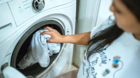 Ama de casa introduce ropa sucia en la lavadora