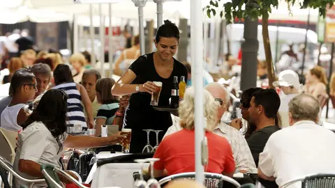 Una camarera atiende una mesa en una terraza