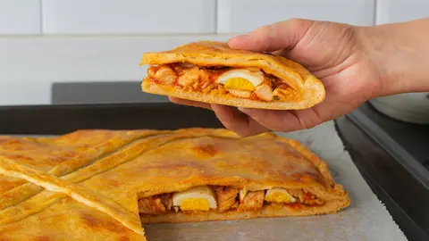 Una empanada rellena de pollo, huevo cocido y sofrito de verduras al horno
