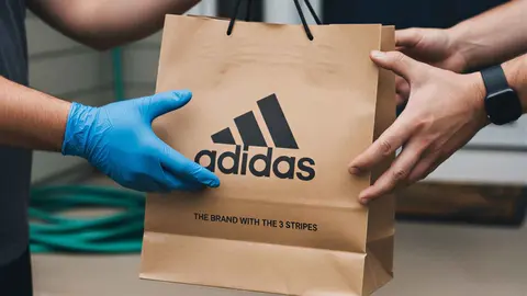 Un repartidor entrega una bolsa de compra de Adidas