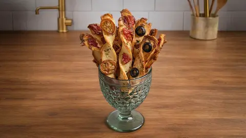 Palitos de hojaldre crujientes con tomates, aceitunas negras y pimientos del piquillo