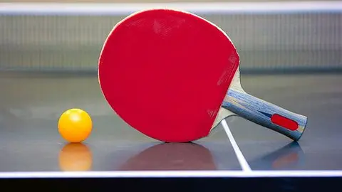 Ping pong ball and racket lying in the corner of the table
