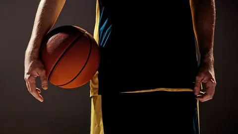 The silhouette view of a basketball player holding basket ball on black background