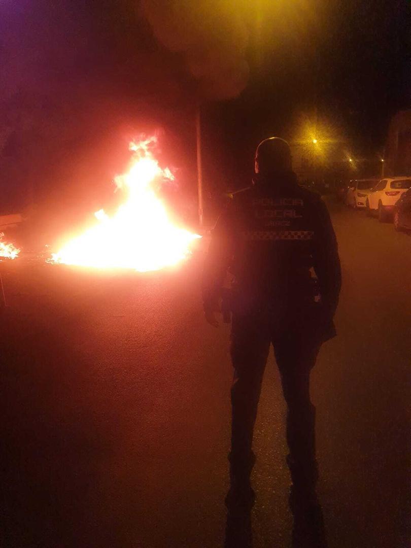 Un agente de la Policía Local de Jerez frente a un contenedor ardiendo
