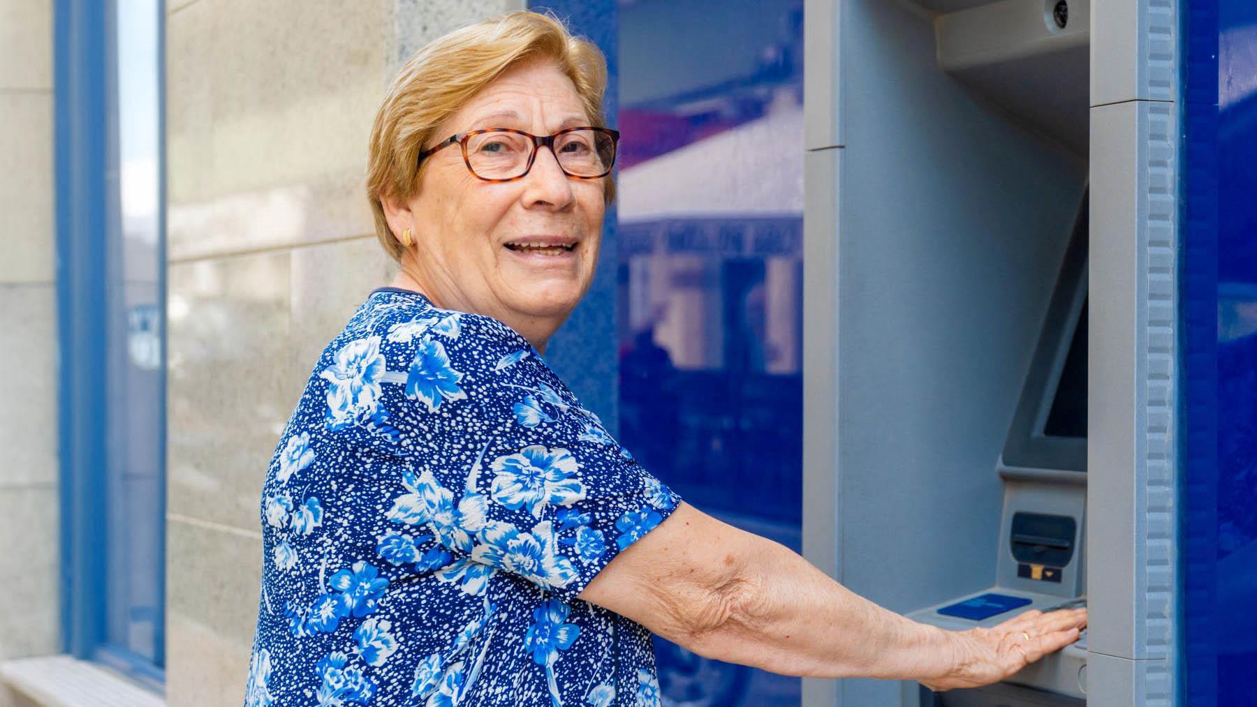Mujer pensionista de la Seguridad Social sacando dinero del banco