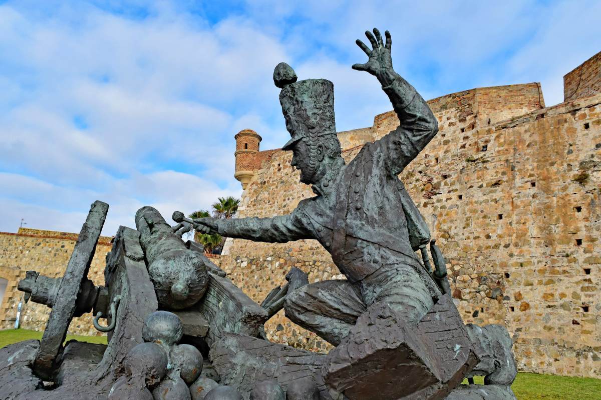 Estatua de bronce de un soldado prendiendo la mecha de un cañón en el Castillo de Ceuta